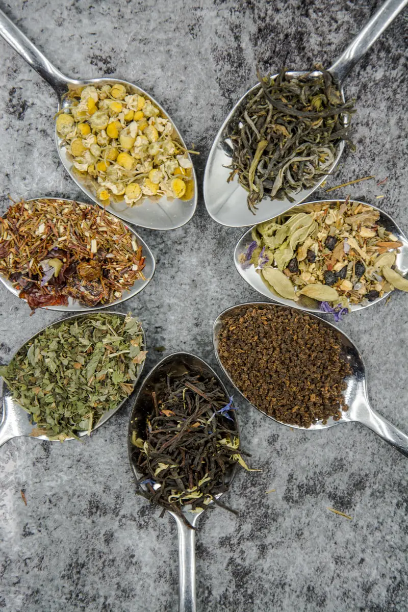 seven different herbs in gray spoons